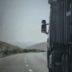 Truck driver performing a roadside safety inspection on a truck and trailer, checking tires and lights before a trip.